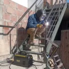 Hombre soldando en una escalera de una casa con la Soldadora VOL-AS160BV