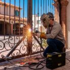 Soldador arreglando puerta metálica de casa con la Soldadora KMI120PRO de Kerher en el día
