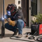 Soldador soldando una puerta de metal con la máquina de soldar EASY MIG140 READY PACK de Lincoln Electric