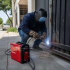 Soldador trabajando en una casa con la soldadora Mega Force 130 E de Lincoln Electric.