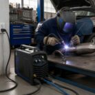 Soldador trabajando con la Soldadora Redbo MMA-200 en una pieza metálica en taller automotriz