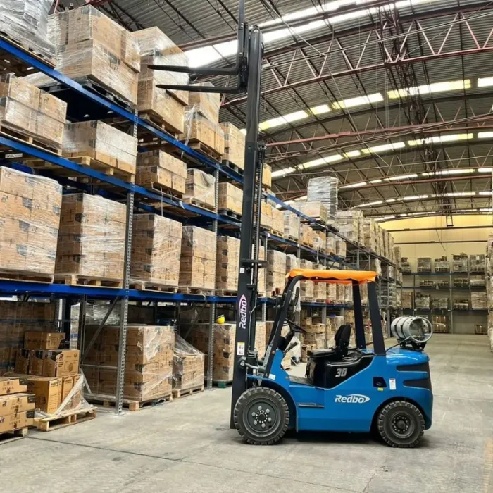 Montacargas Redbo HH30 con mástil elevado Montacargas Redbo HH30 con el mástil elevado junto a racks de almacén