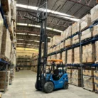 Montacargas Redbo con el mástil extendido en un almacén con racks altos